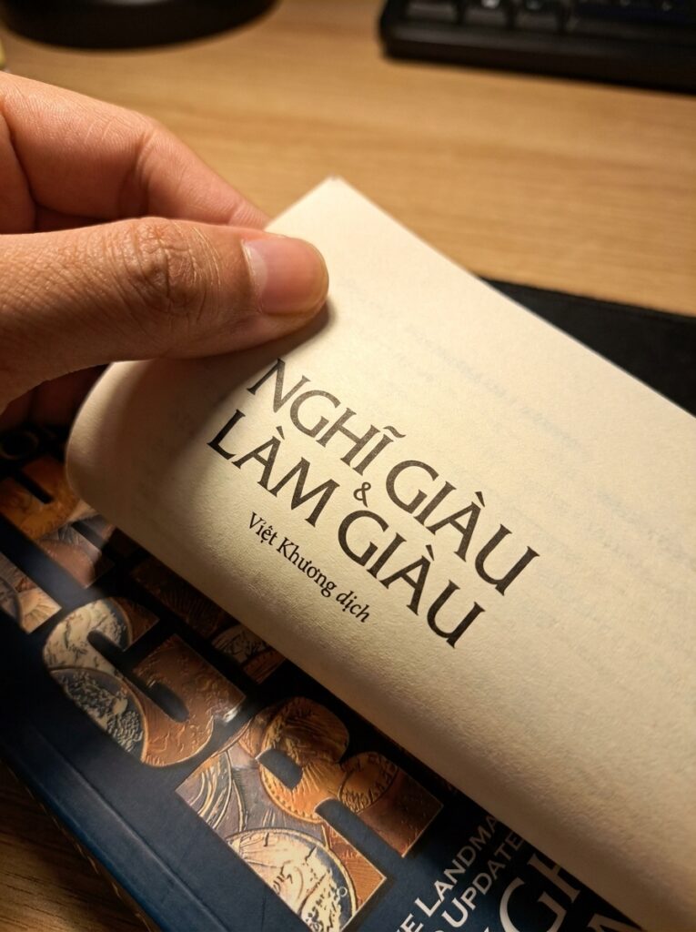 Để Có Được Sự Giàu Có Trong Cuộc Sống Thì Cần Bắt Đầu Từ Tư Duy: Đọc "Nghĩ Giàu Làm Giàu" Dưới Góc Nhìn Freelancer Hand Turning Book Page 202607181251 765x1024